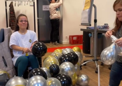 Personen pusten silber und goldene Luftballons auf und dekorieren einen Raum