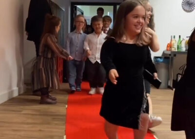 Jugendliche in festlicher Kleidung jubeln auf dem roten Teppich bei der "Prom Night" Veranstaltung.