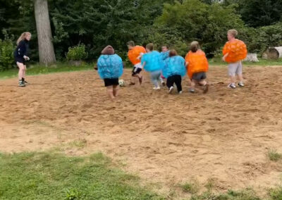 Jugendliche während eines Bubble-Soccer-Spiels auf einem Sandfeld, in große aufblasbare Kunststoffbälle gehüllt